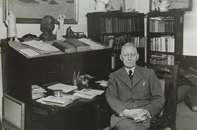 Fotografi af Johannes V. Jensen, der sidder ved et skrivebord.